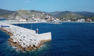 a large concrete wall with a body of water and a city in the background