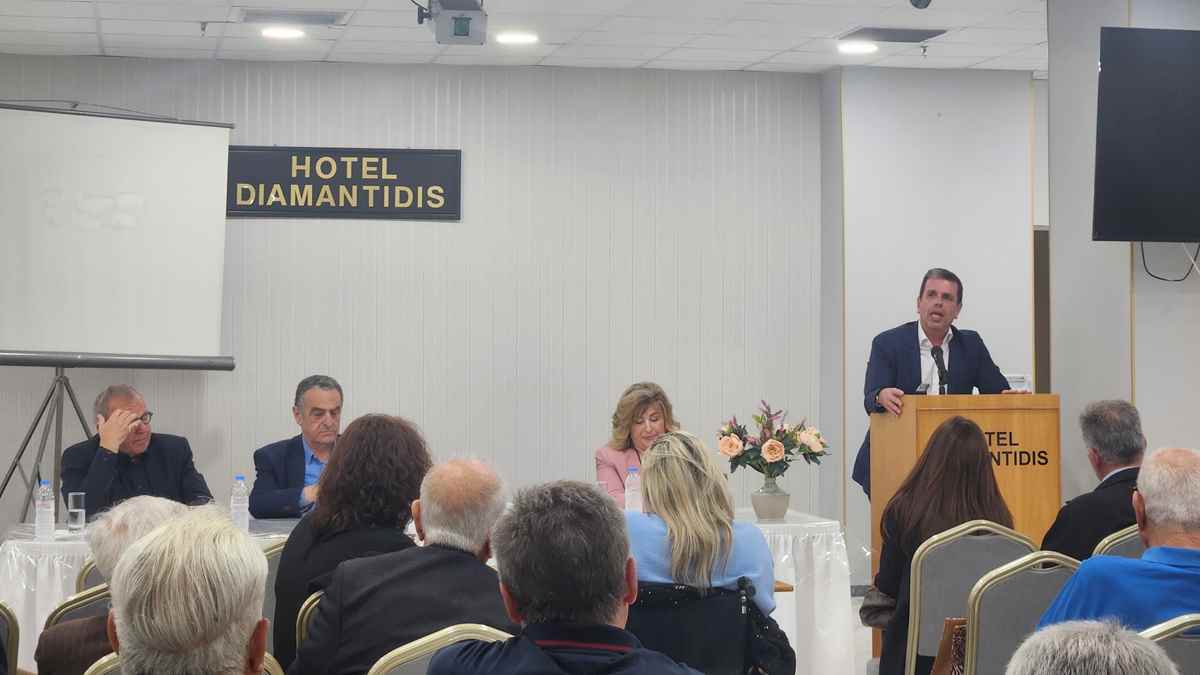 a man standing at a podium with a group of people sitting in chairs
