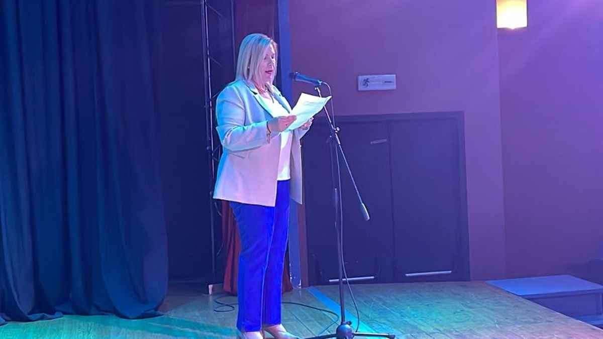 a woman standing on a stage holding a piece of paper