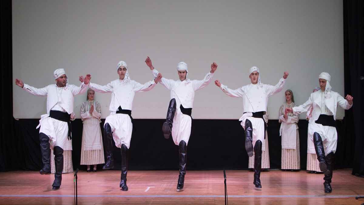 a group of people in white clothes dancing on a stage