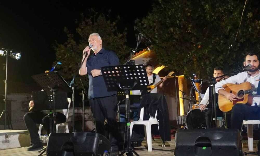a man singing into a microphone on a stage with other people playing instruments