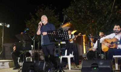 a man singing into a microphone on a stage with other people playing instruments
