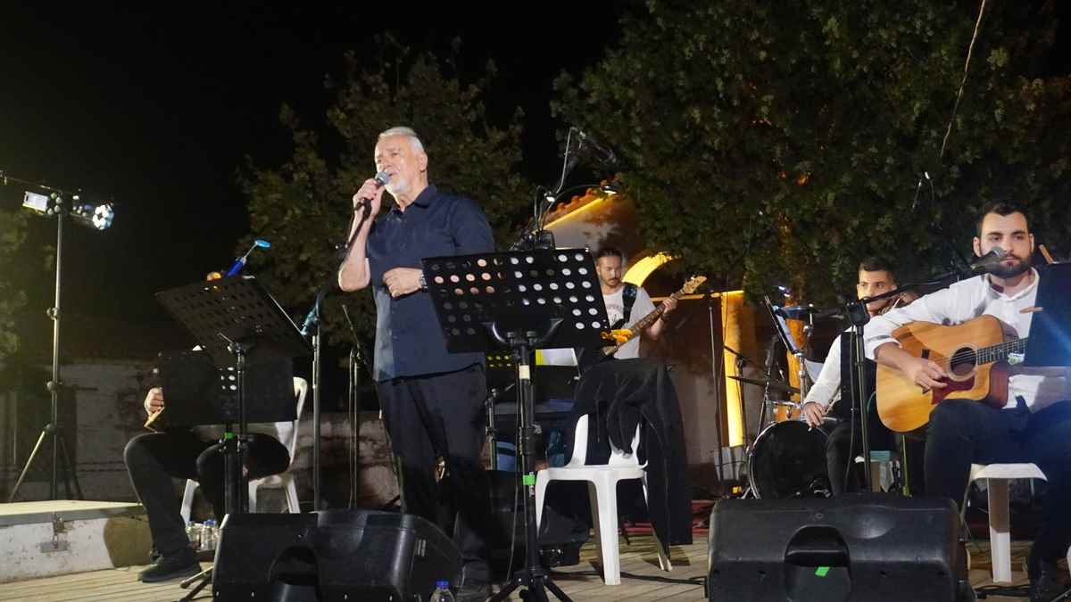 a man singing into a microphone on a stage with other people playing instruments