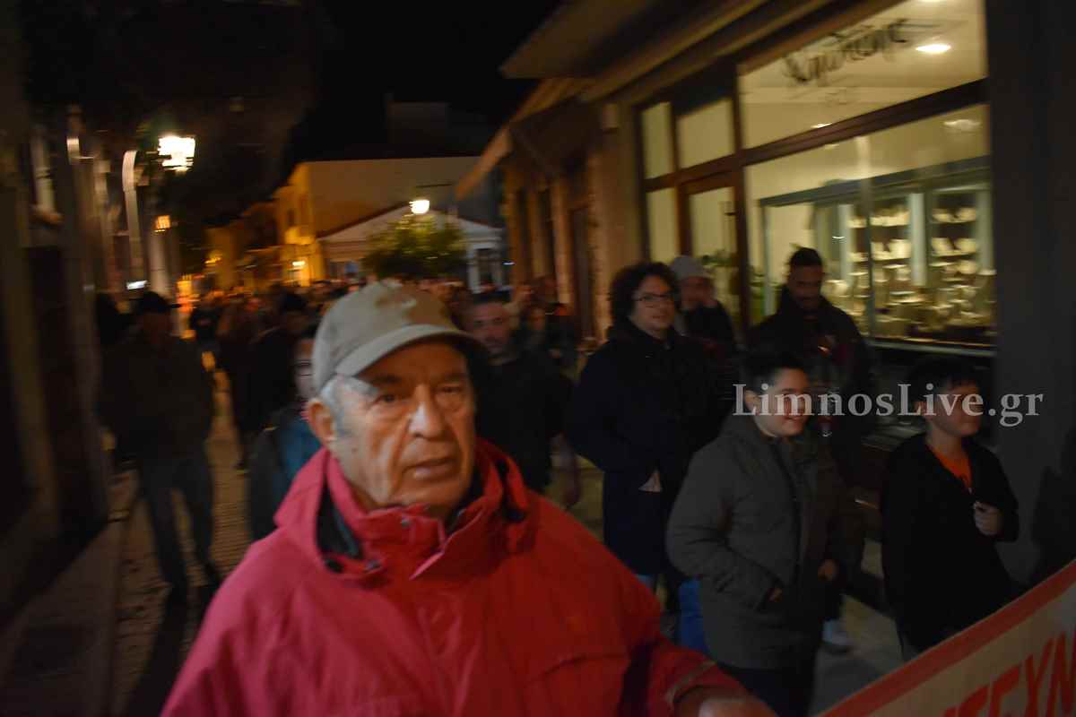 a man in a red jacket and cap standing in front of a crowd of people