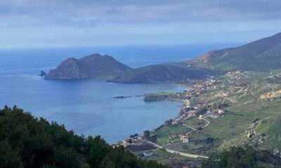 a landscape of a body of water with a town and mountains