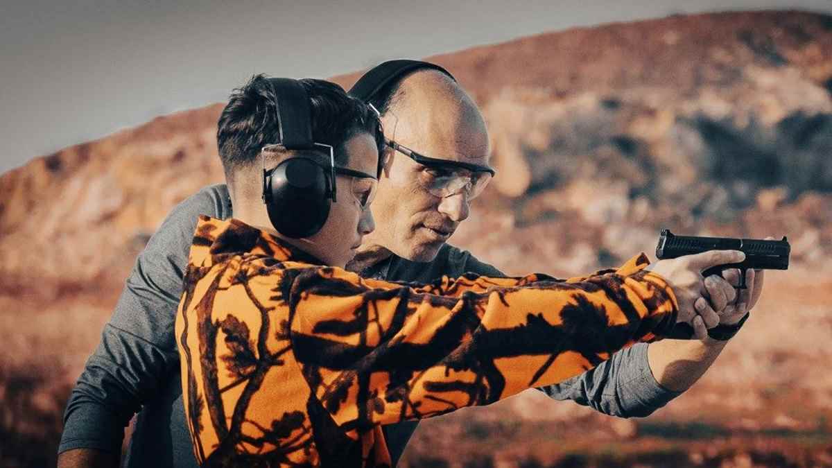 a man and boy wearing headphones and holding a gun