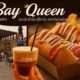 a hand holding a drink and a hot dog in a restaurant