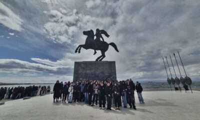 Ομάδα ανθρώπων μπροστά σε άγαλμα.